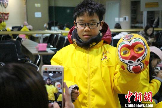 为“孙悟空”脸谱上色完成后，带队老师为一学生拍照留念。　赵晓 摄